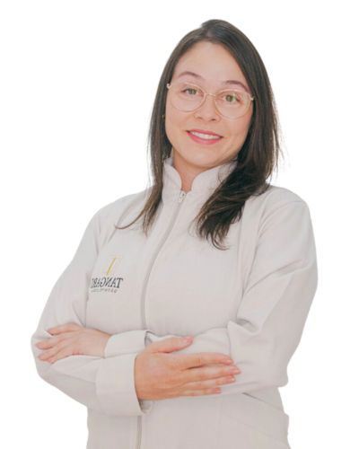 Imagem da Doutora Graziella, de cabelos longos e escuros, vestindo um jaleco branco com o logotipo da Tangari Odontologia no lado direito. Ela está com os braços cruzados e olha diretamente para a câmera, transmitindo uma expressão de simpatia e profissionalismo.